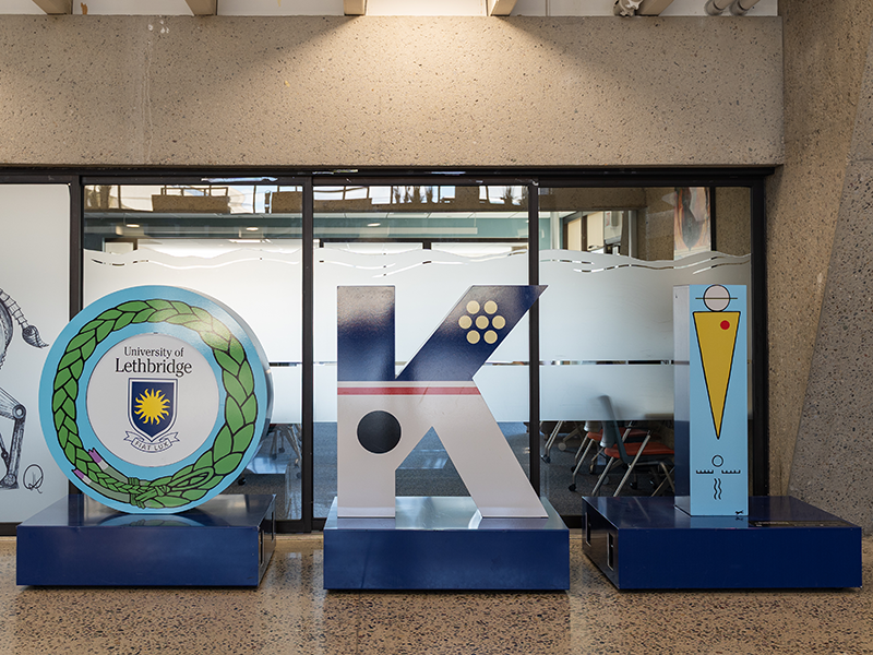OKI by Api’soomaahka (William Singer III) OKI sculpture by Api’soomaahka (William Singer III) inside the University of Lethbridge 6th floor atrium. Sweetgrass and pictograms are depicted across the letters.
