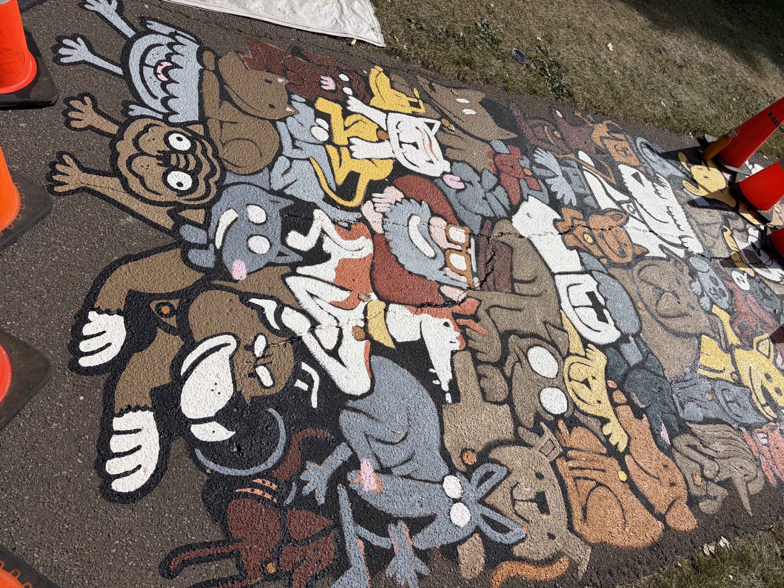 Dogpile asphalt mural mid-creation.  Many dogs being painted on the sidewalk. 